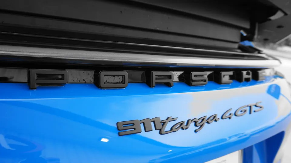 Close-up of the rear badging on a blue Porsche 911 Targa 4 GTS, showing the 'Porsche' and '911 Targa 4 GTS' emblems.