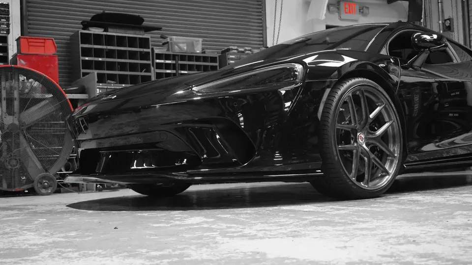 Black McLaren supercar with custom HF wheels parked in a performance tuning shop.