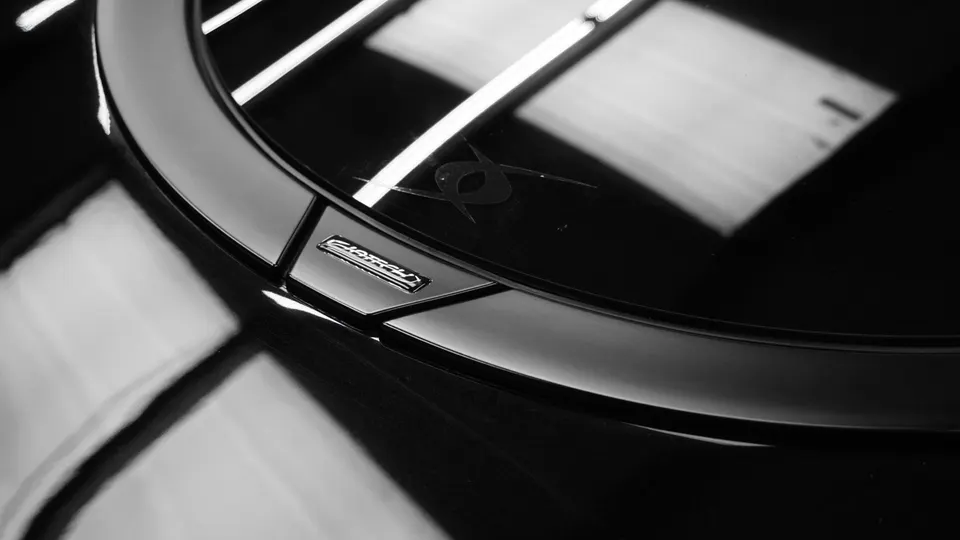 Close-up black and white detail of a Jotech Motorsports car emblem on a glossy black surface