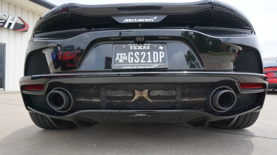 Rear view of a black McLaren sports car showcasing its dual exhaust system and aggressive diffuser.