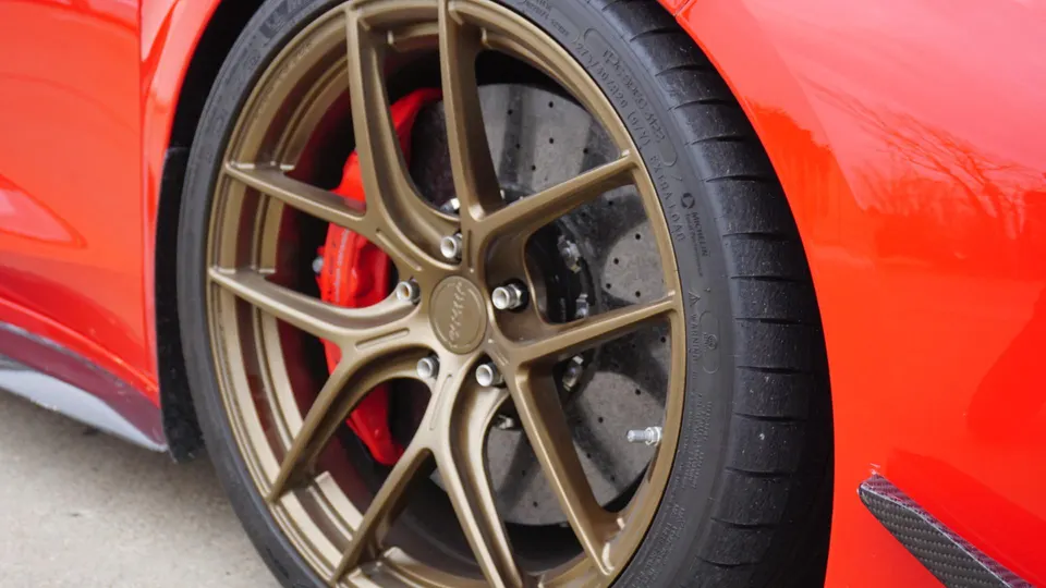 Close-up of a red car's bronze custom wheels with red brake calipers and drilled rotors.