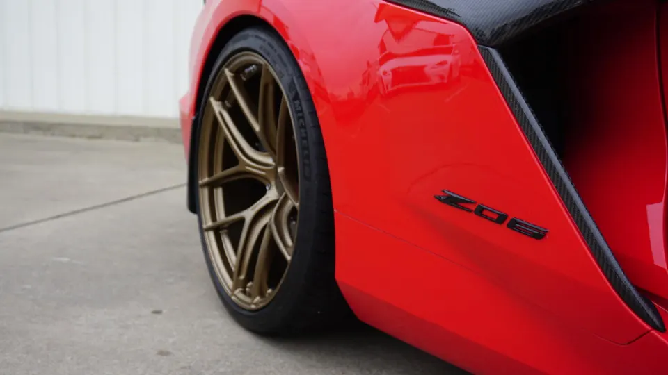 Close-up of a red Corvette Z06 rear fender with bronze multi-spoke wheels and Michelin tires.