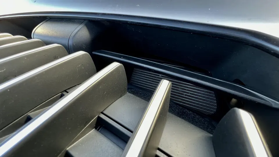 Close-up view of a car's front grille revealing a radiator or intercooler behind the slats.