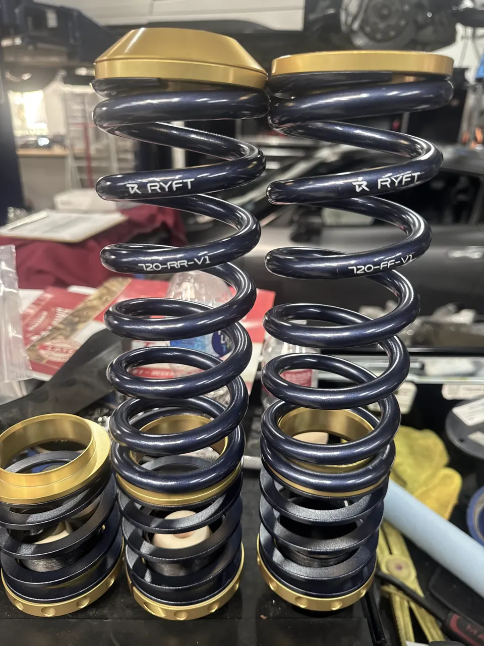 RYFT suspension springs and coilover components on a workbench in a performance tuning shop