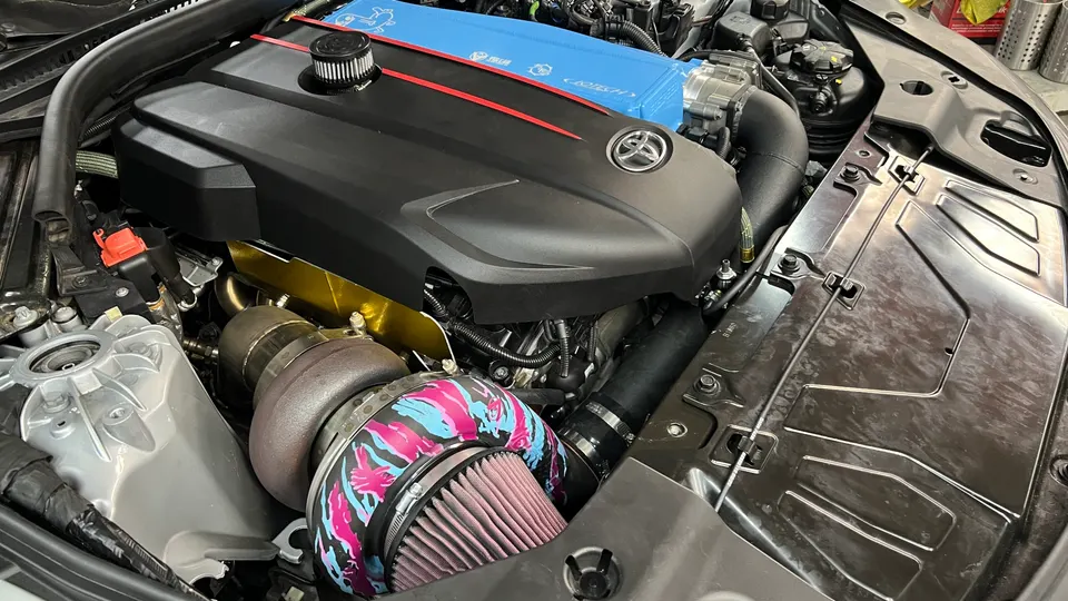 Close-up of a modified Toyota Supra B58 engine bay featuring a large turbocharger and aftermarket intake.