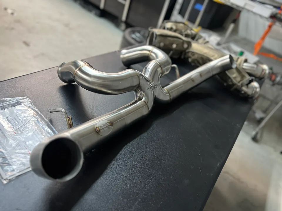 Fabspeed stainless steel exhaust system on a workbench in a performance tuning shop.