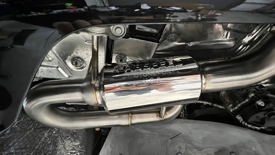 Close-up of a Fabspeed Motorsport stainless steel exhaust system installed on a performance car's undercarriage.