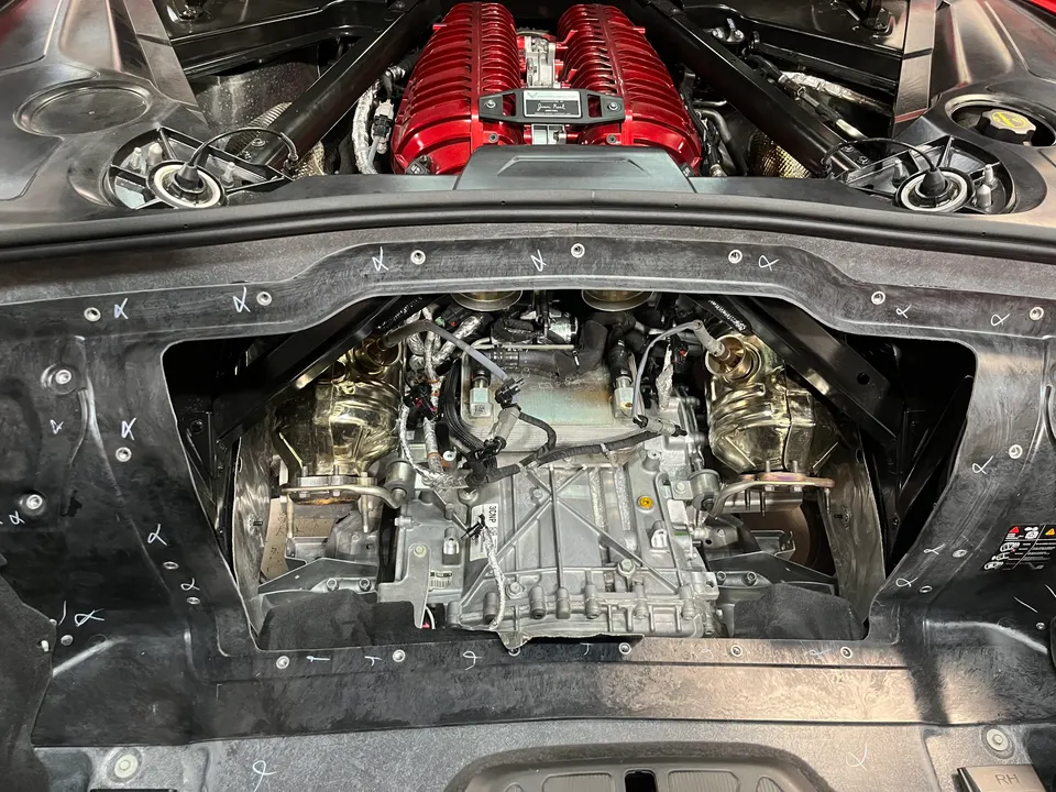 Detailed view of a C8 Corvette engine bay showcasing a red performance intake manifold and exhaust system.