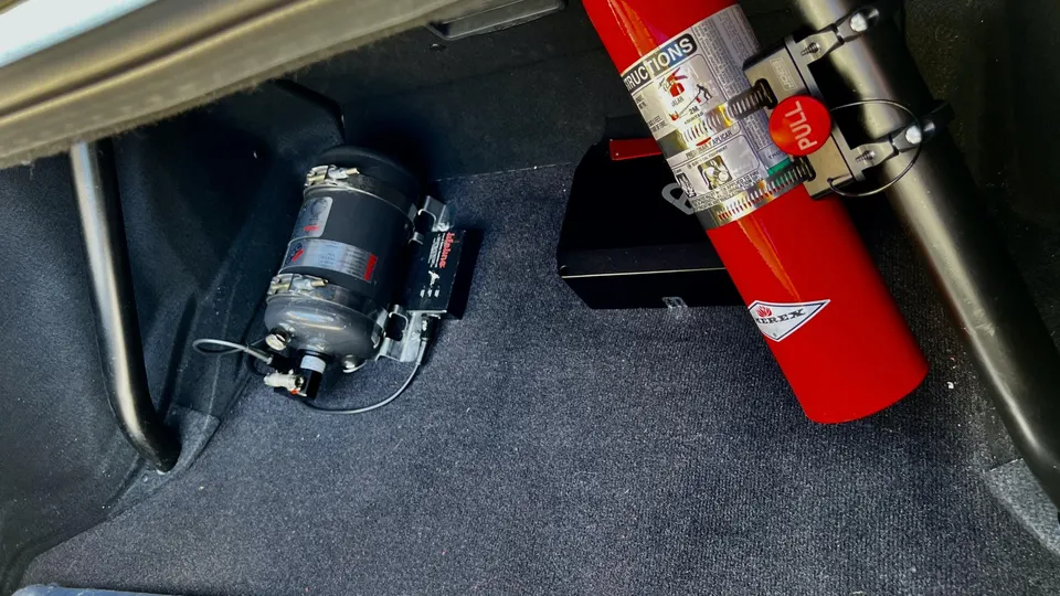 Fuel surge tank and fire extinguisher installed in the trunk of a performance car.