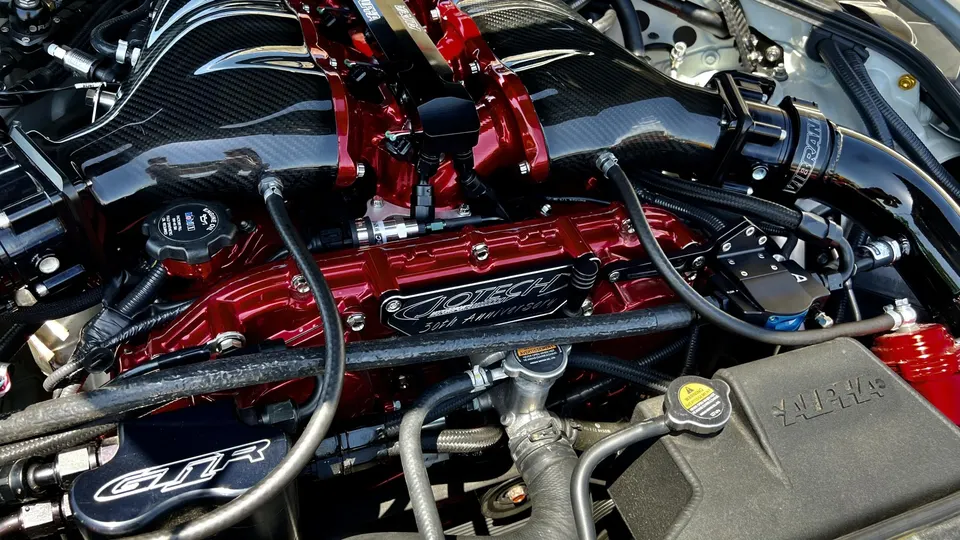 Close-up of a custom Nissan GT-R engine bay featuring a red Jotech intake manifold and carbon fiber induction system.