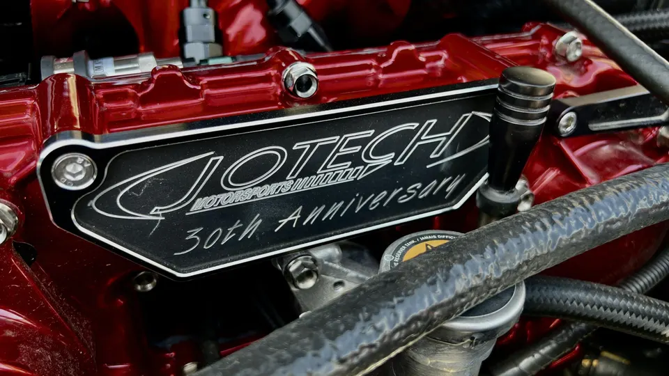 A close-up of a red Jotech Motorsports 30th Anniversary valve cover in an engine bay.