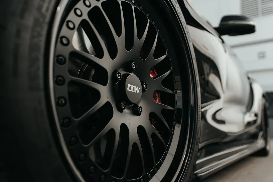 Close-up of a black custom CCW wheel with red brake calipers on a performance car.