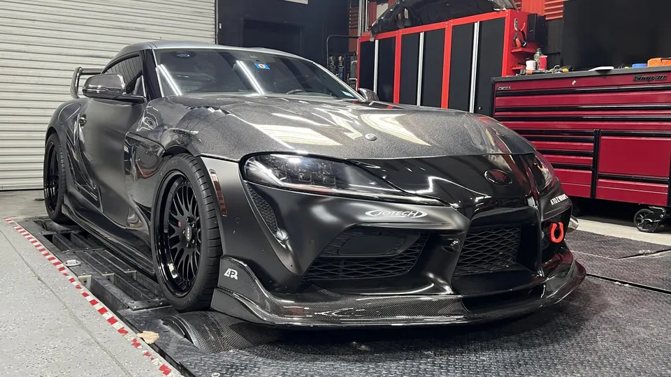 Matte black Toyota Supra with carbon fiber body kit and aftermarket wheels on a dyno at Jotech Motorsports.