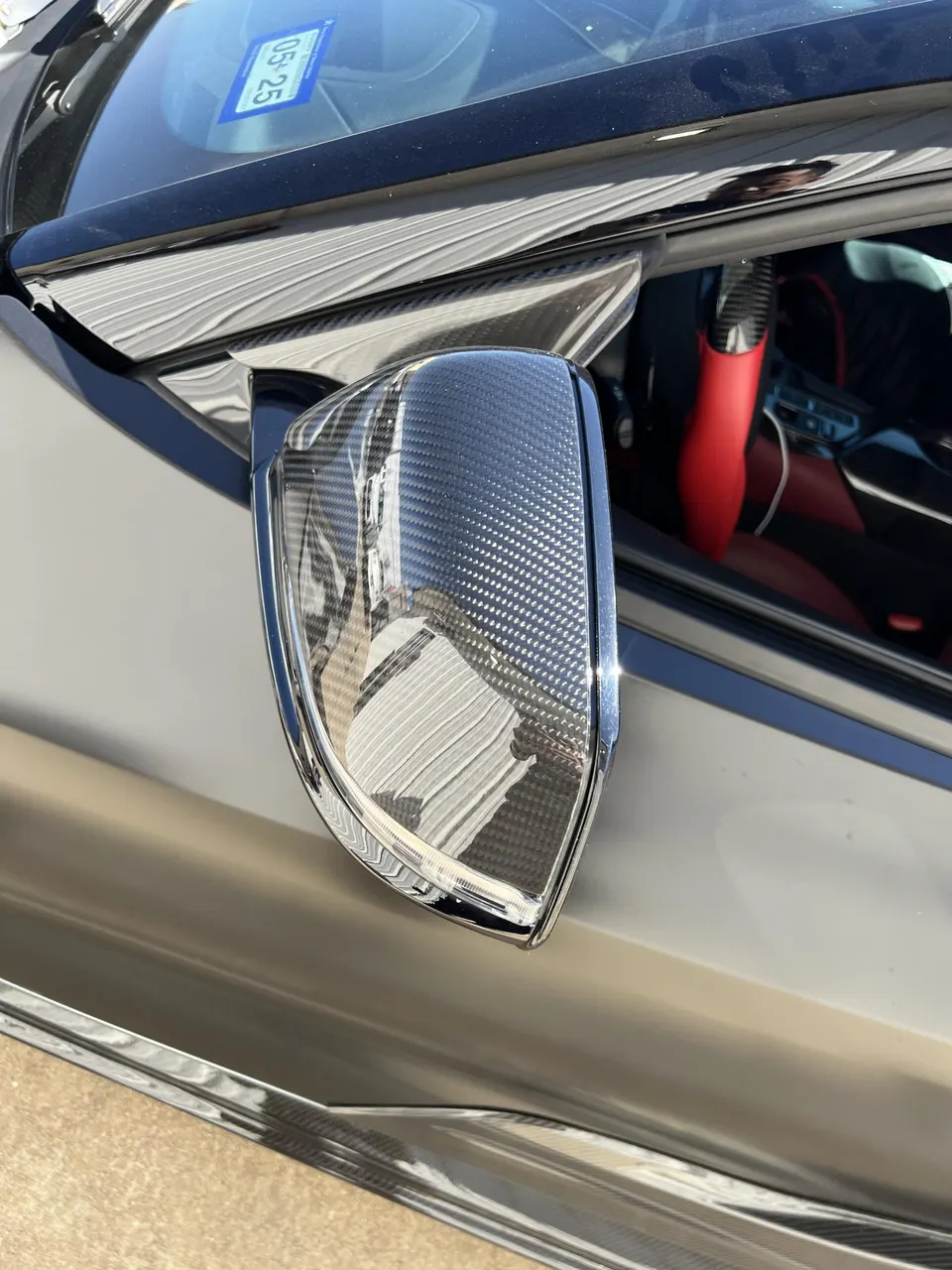 A close-up of a carbon fiber side mirror on a grey Corvette C8.