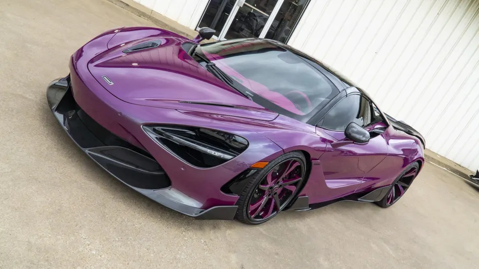 A custom purple McLaren 720S with carbon fiber aero and matching purple custom wheels parked outdoors.