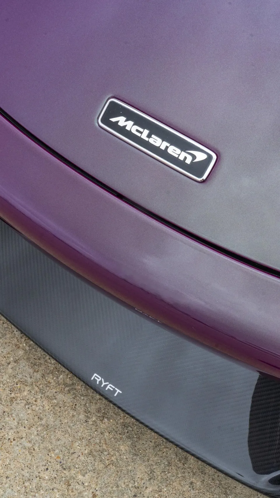 Close-up of a purple McLaren's front bumper with a carbon fiber RYFT splitter and McLaren badge.