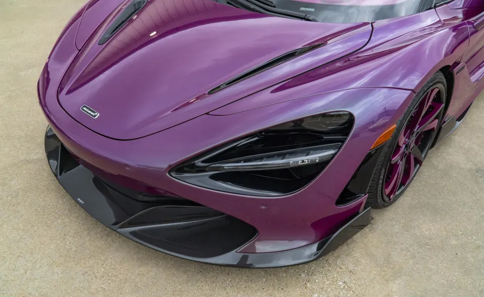 A purple McLaren 720S with a carbon fiber front splitter and custom purple wheels.