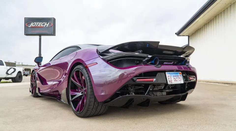 A purple McLaren 720S with custom wheels and a large rear wing parked outside Jotech Motorsports.
