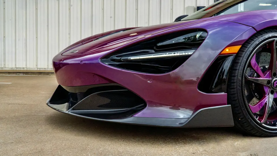 Close-up of a purple McLaren 720S featuring a carbon fiber front splitter and custom purple wheels.