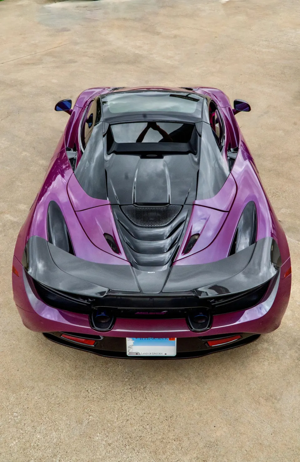 A high-angle rear view of a purple McLaren 720S with a carbon fiber active rear wing and diffuser.