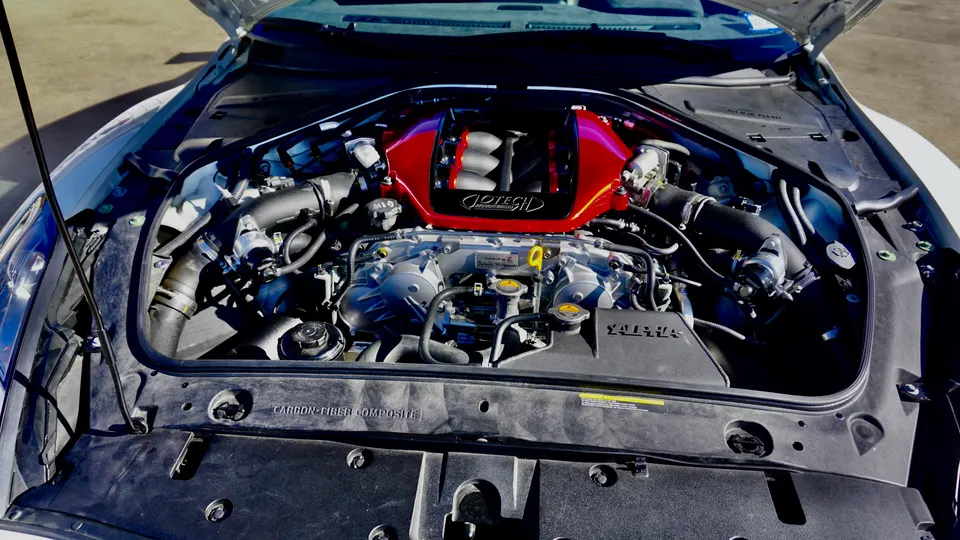 Close-up of a Jotech tuned Nissan GT-R VR38DETT engine bay with a custom red intake manifold and performance upgrades.