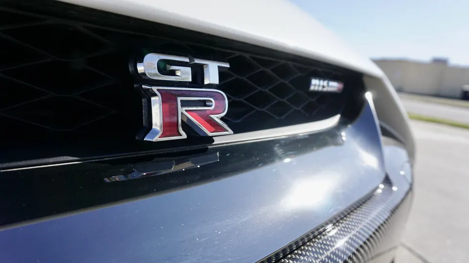 Close-up of a Nissan GT-R Nismo front bumper featuring the GT-R and Nismo badges and carbon fiber trim.