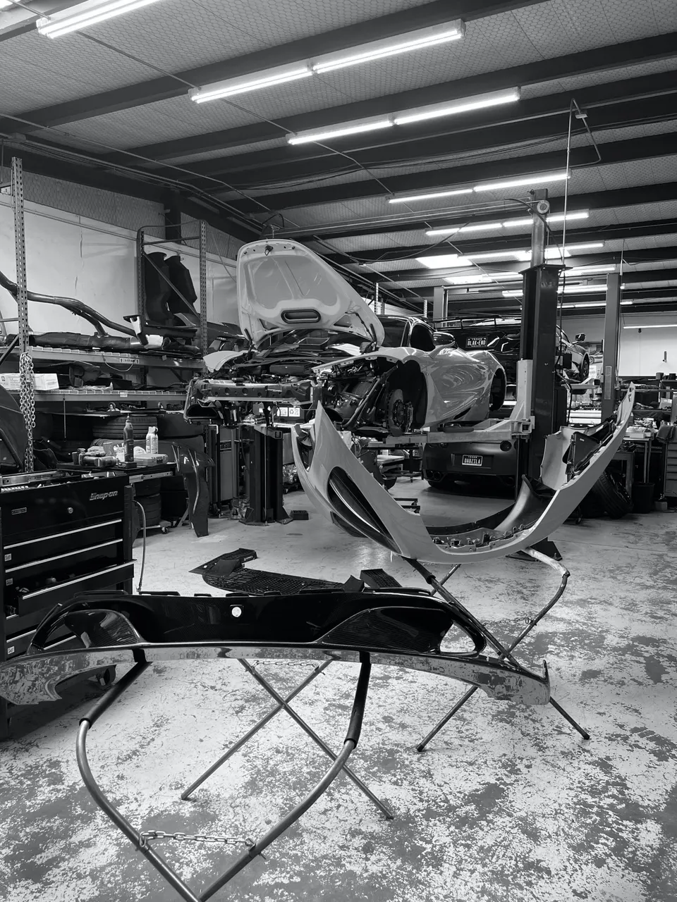 A Toyota Supra undergoing disassembly and repair in a performance tuning shop, with body panels removed and on stands.