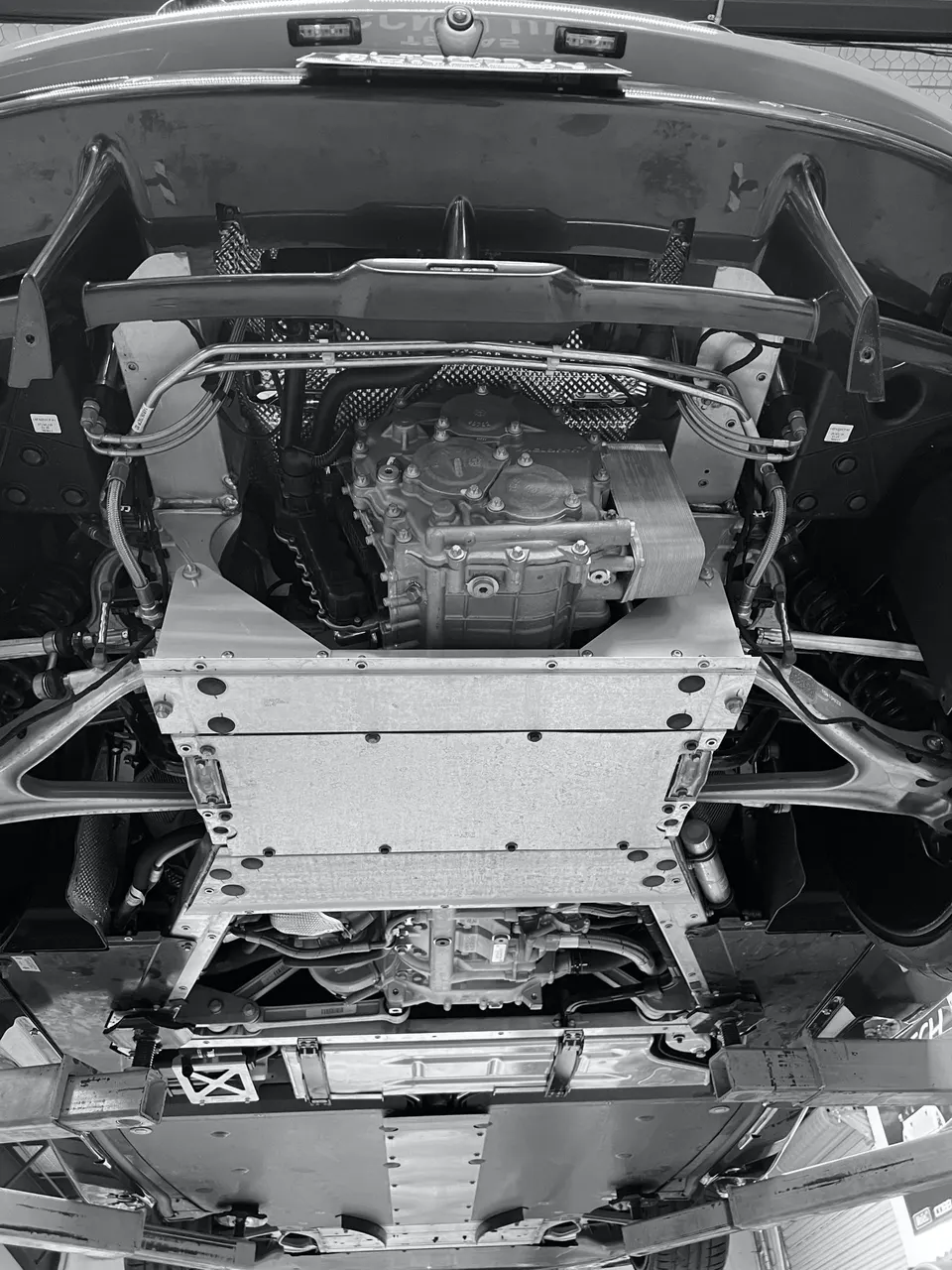 Underside view of a high-performance car on a lift, showcasing the transmission, drivetrain, and chassis components.