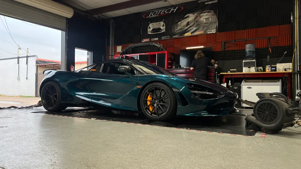 A green McLaren 720S strapped to a dynamometer at Jotech Motorsports for performance tuning.