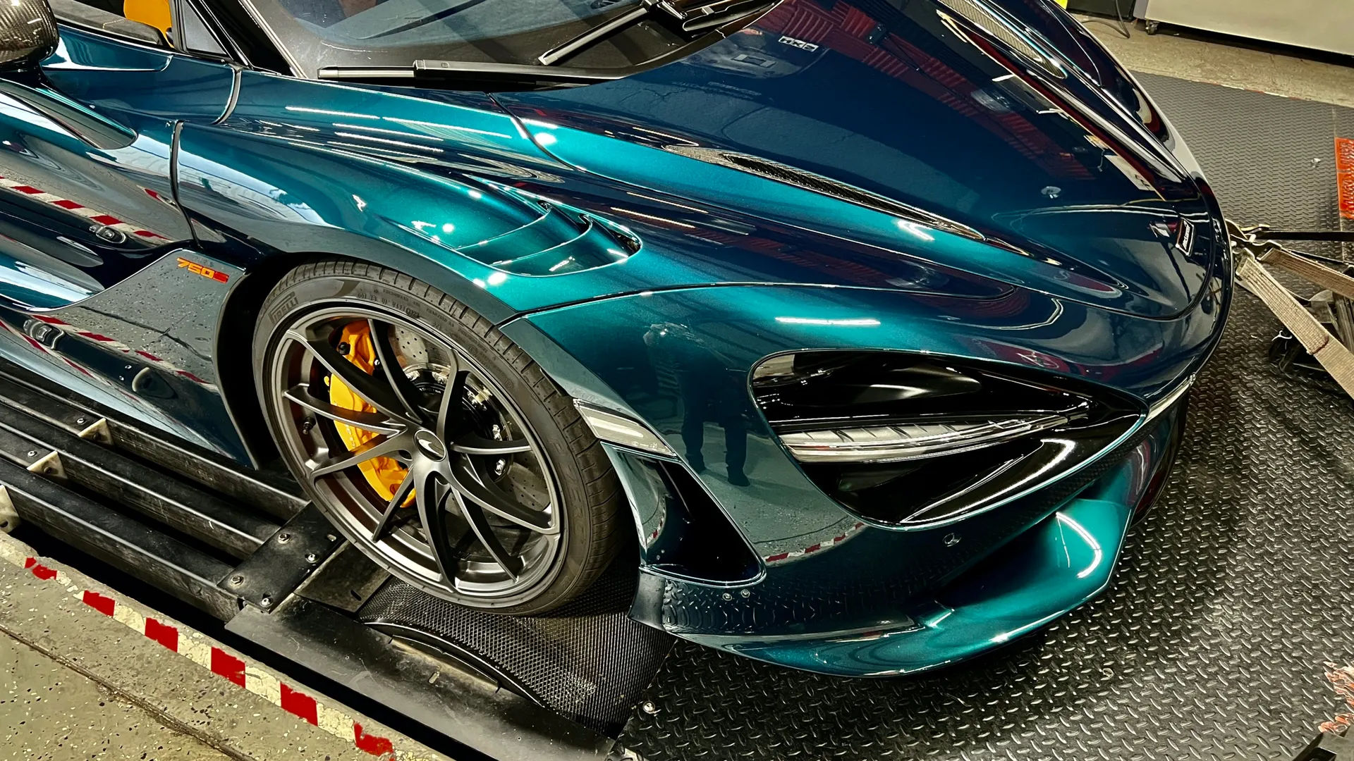 A green McLaren 750S supercar strapped to a dynamometer for performance testing.