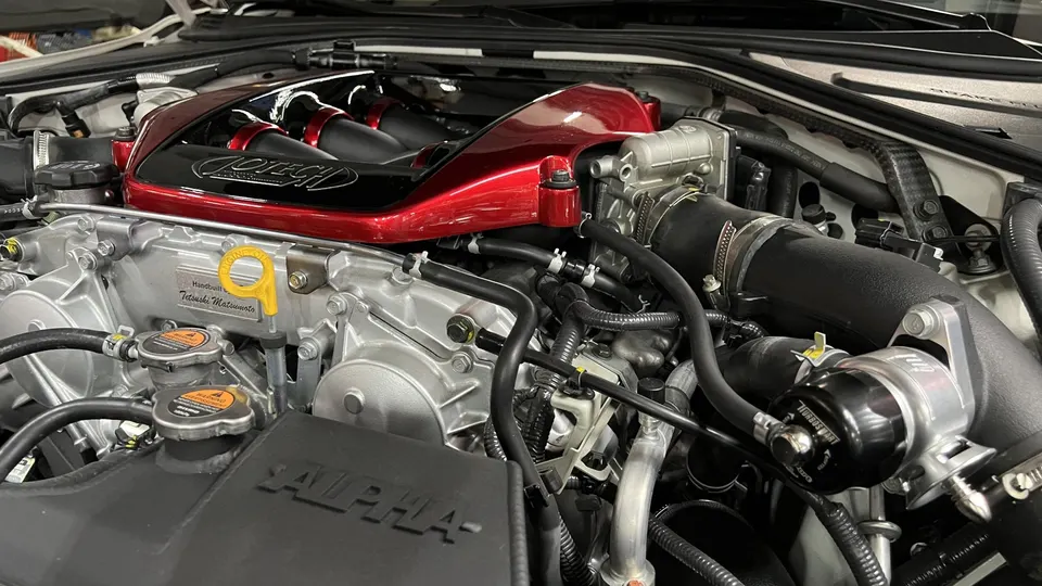 Close-up of a Jotech tuned engine bay featuring a red and black intake manifold and Turbosmart blow-off valve.
