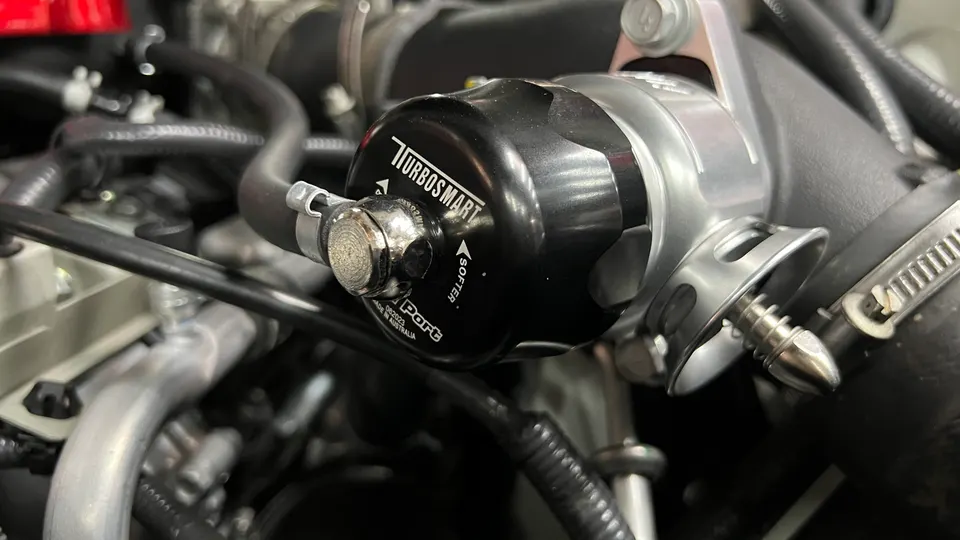 Close-up of a Turbosmart blow-off valve installed in a performance car's engine bay.