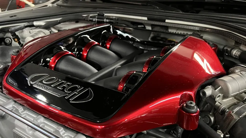 Close-up of a Jotech custom red and black intake manifold in a high-performance car engine bay.
