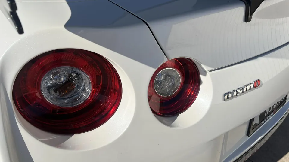 Close-up of the rear of a white Nissan GT-R Nismo, showcasing its iconic round taillights and Nismo badge.