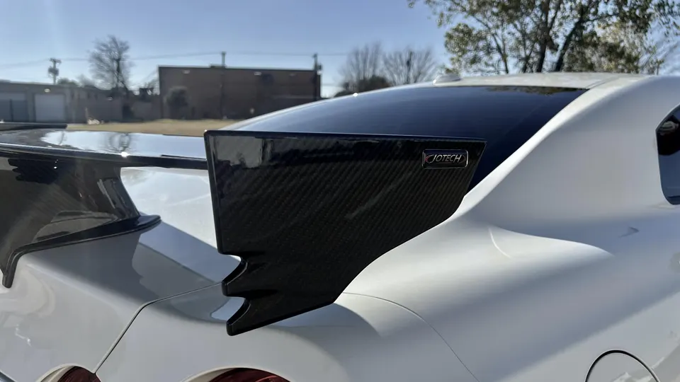 Close-up of a white Nissan GT-R's carbon fiber rear wing with a Jotech logo, showcasing exterior aero.