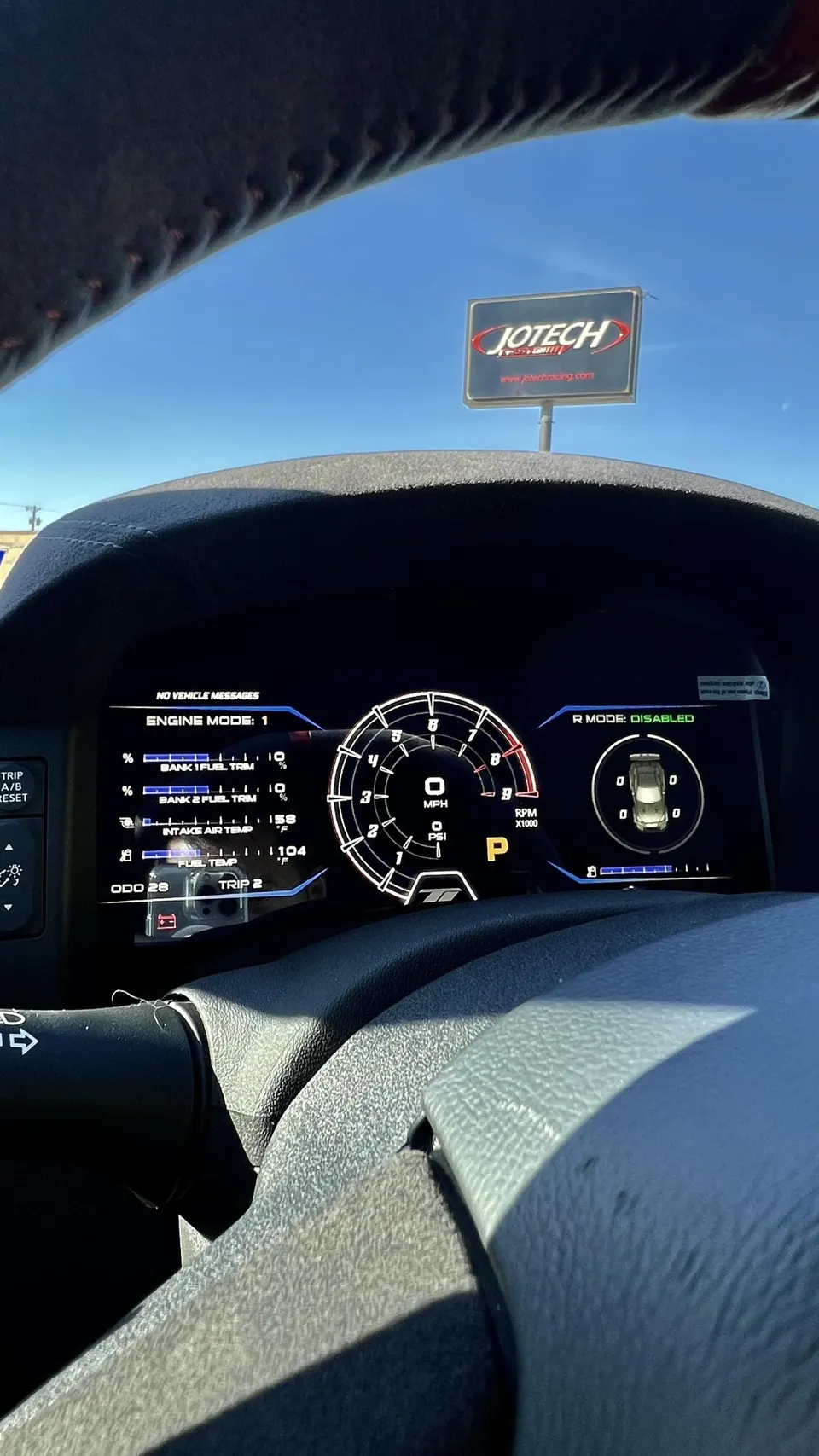 Digital dashboard displaying engine parameters and performance data inside a car at Jotech Motorsports.