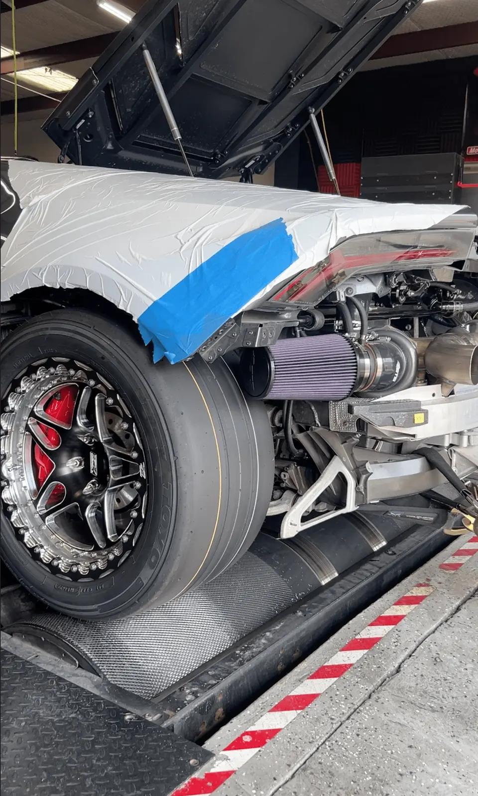 Lamborghini Huracan on a dyno with exposed turbocharger and air filter, featuring drag wheels and red brake calipers.