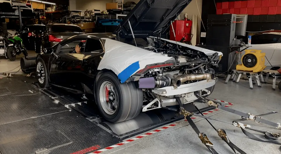A black Lamborghini Huracan on a dyno with its rear bumper removed, showcasing a twin-turbo setup.