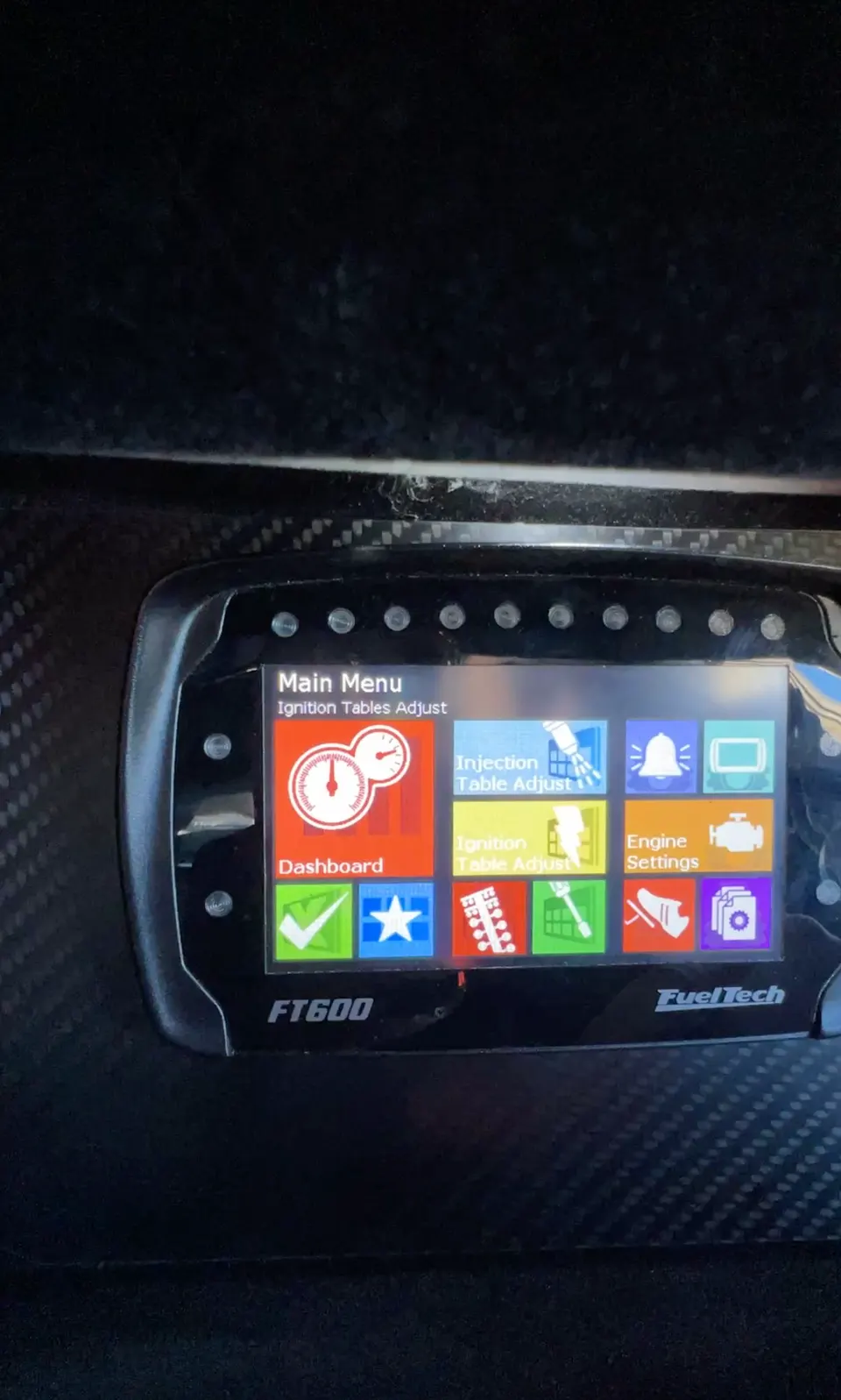 Close-up of a FuelTech FT600 digital dash displaying the main menu for engine management and tuning.