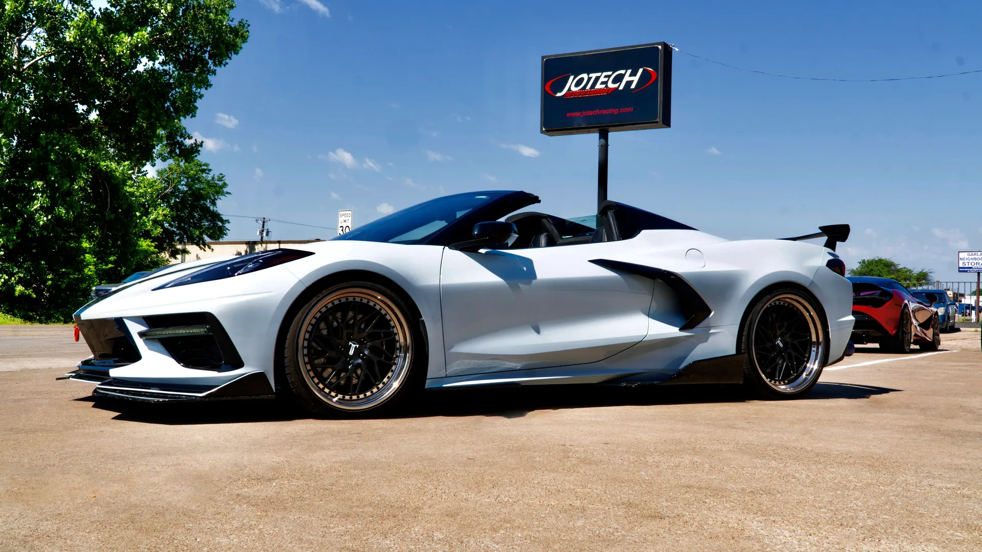White C8 Corvette convertible with aftermarket wheels, front splitter, and rear wing parked outside Jotech Motorsports.