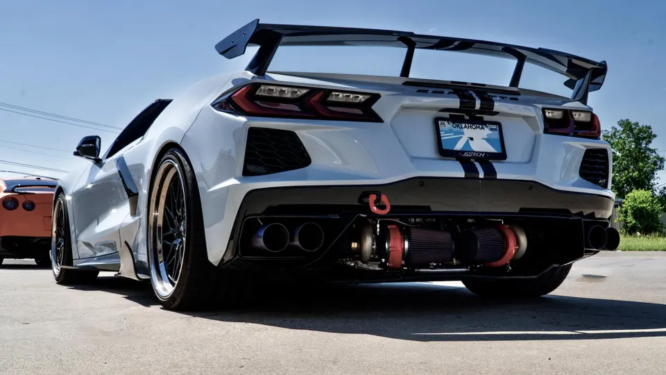 Rear view of a white widebody Corvette C8.R with exposed twin turbos, a large rear wing, and custom exhaust.