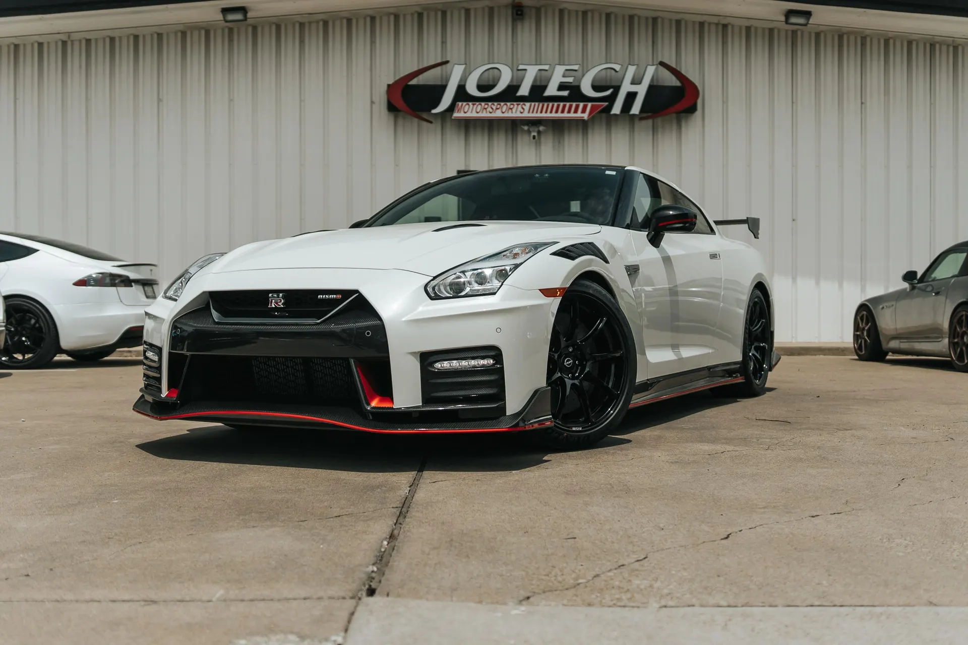 White Nissan GT-R Nismo parked outside Jotech Motorsports performance tuning shop.
