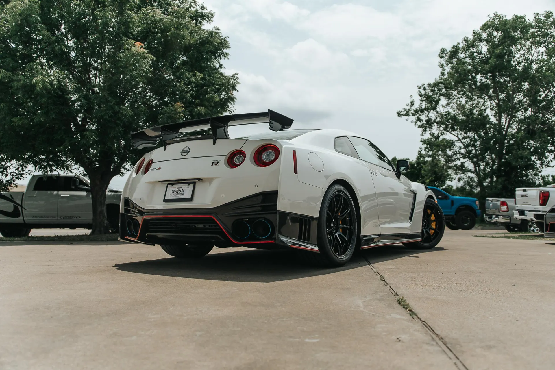 White Nissan GT-R with a large carbon fiber wing and aggressive rear diffuser parked outdoors.