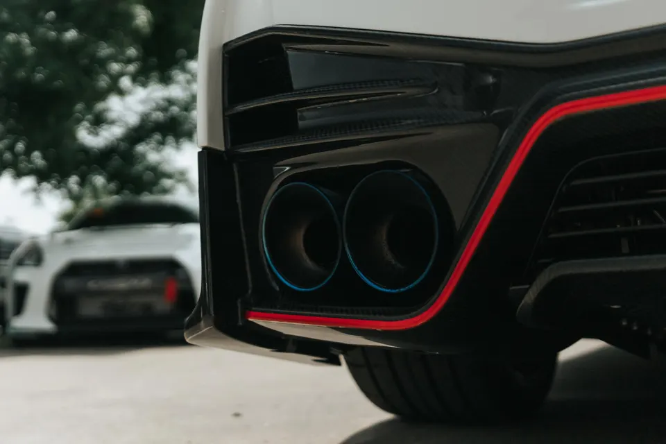 Close-up of a white Nissan GT-R's rear bumper with blue-tipped aftermarket exhaust and carbon fiber diffuser.