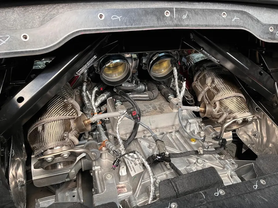 Close-up view of a high-performance engine bay with twin turbochargers, heat shields, and throttle bodies during a custom build.