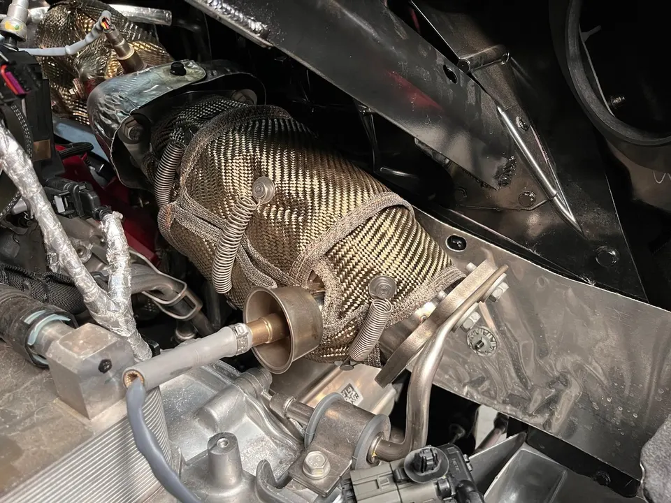 Close-up of a heat-wrapped exhaust manifold or turbo component in a high-performance engine bay.
