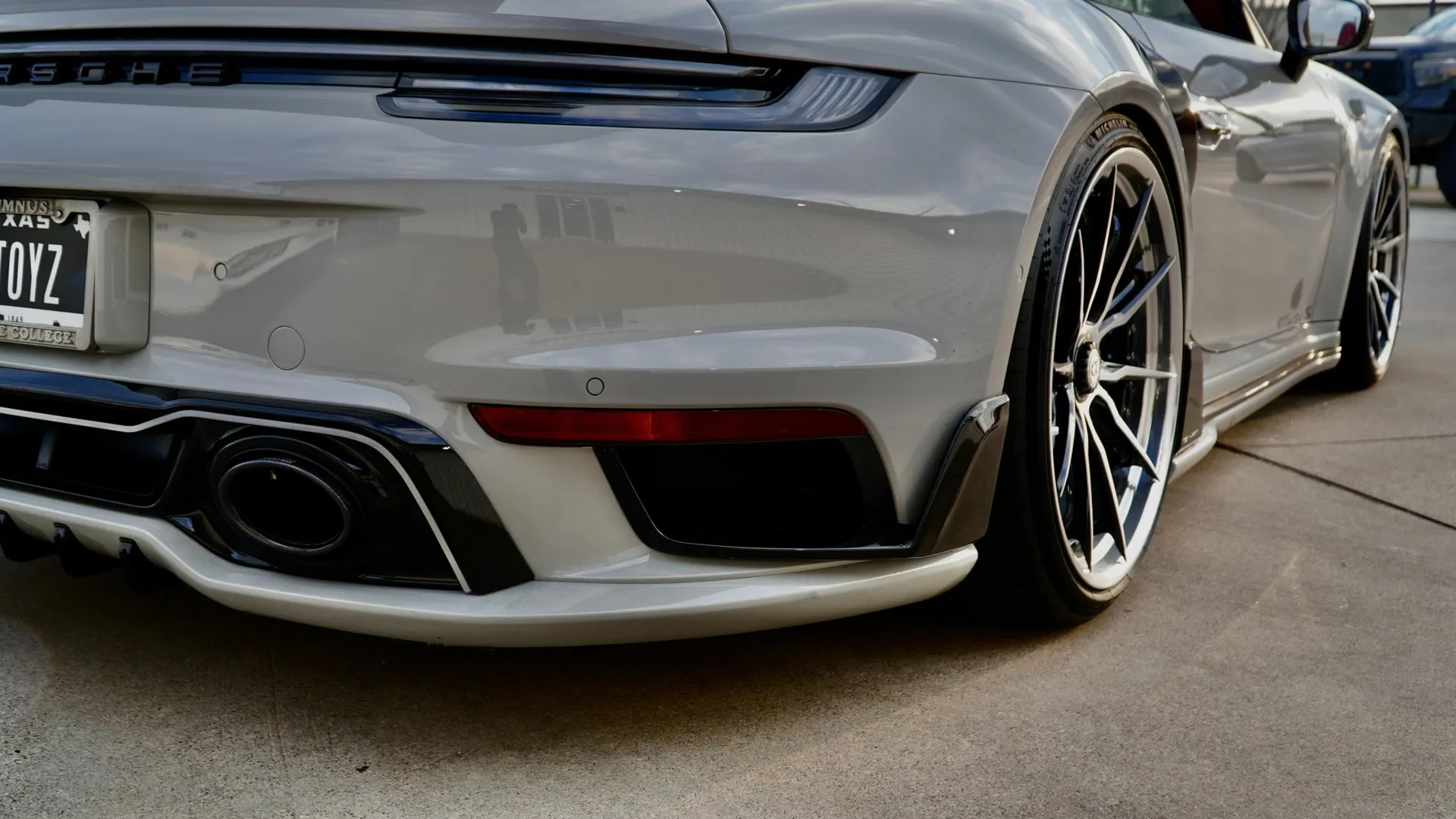 Rear view of a grey Porsche 911 with aftermarket exhaust tips and a custom rear diffuser.