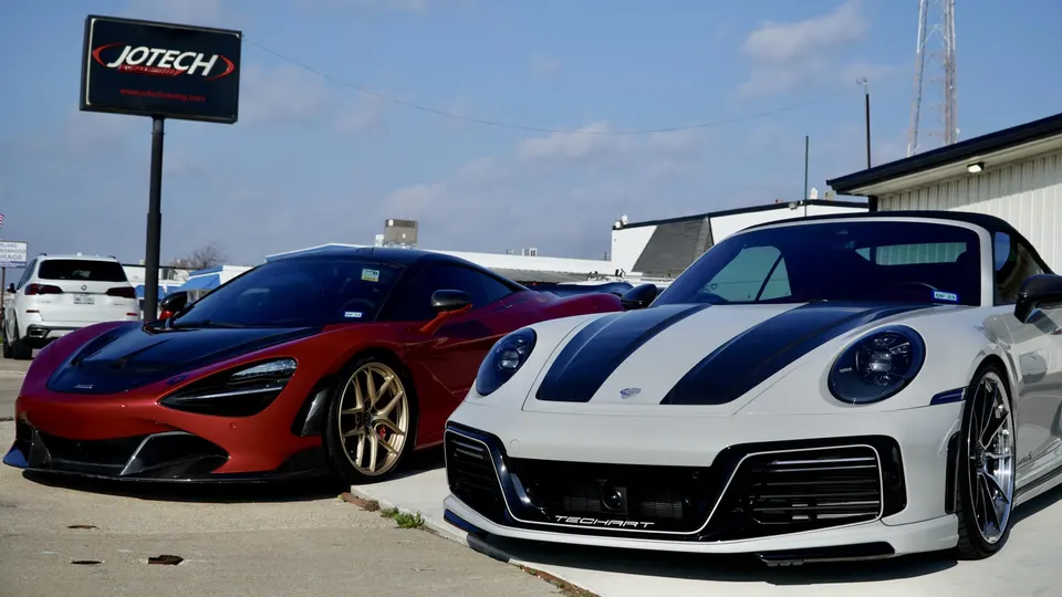 Red McLaren 720S and white Techart Porsche 911 parked outside Jotech Motorsports performance shop.