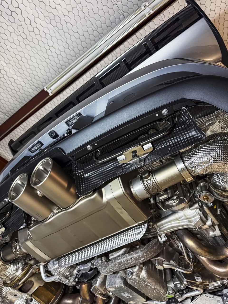 Underside view of a Porsche with a performance exhaust system installed, showing mufflers and tips.