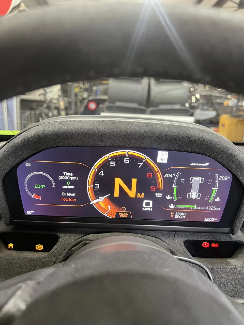 McLaren digital dashboard displaying "Oil level Too low" and other vehicle information.